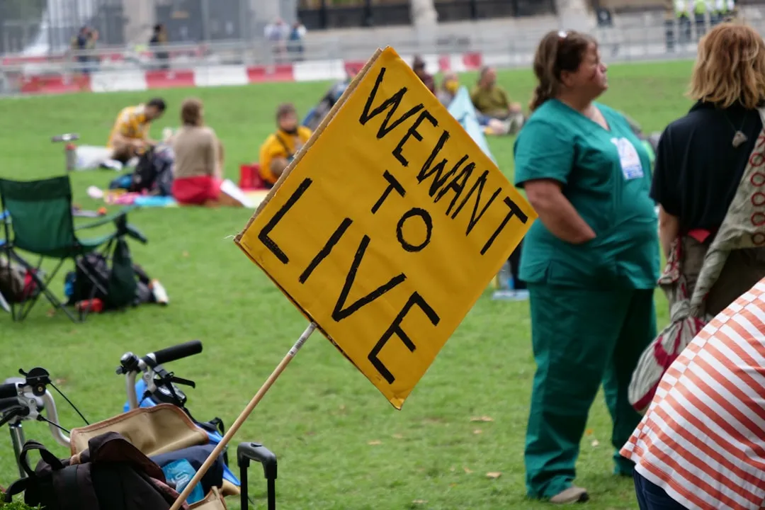 Homem de jaqueta azul segurando uma placa de trânsito amarela e preta