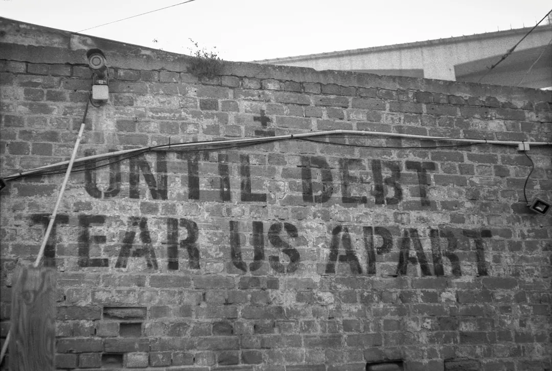 Uma placa em uma parede de tijolos que diz até que a dívida se desfaça Uma placa em uma parede de tijolos que diz até que a dívida se desfaça