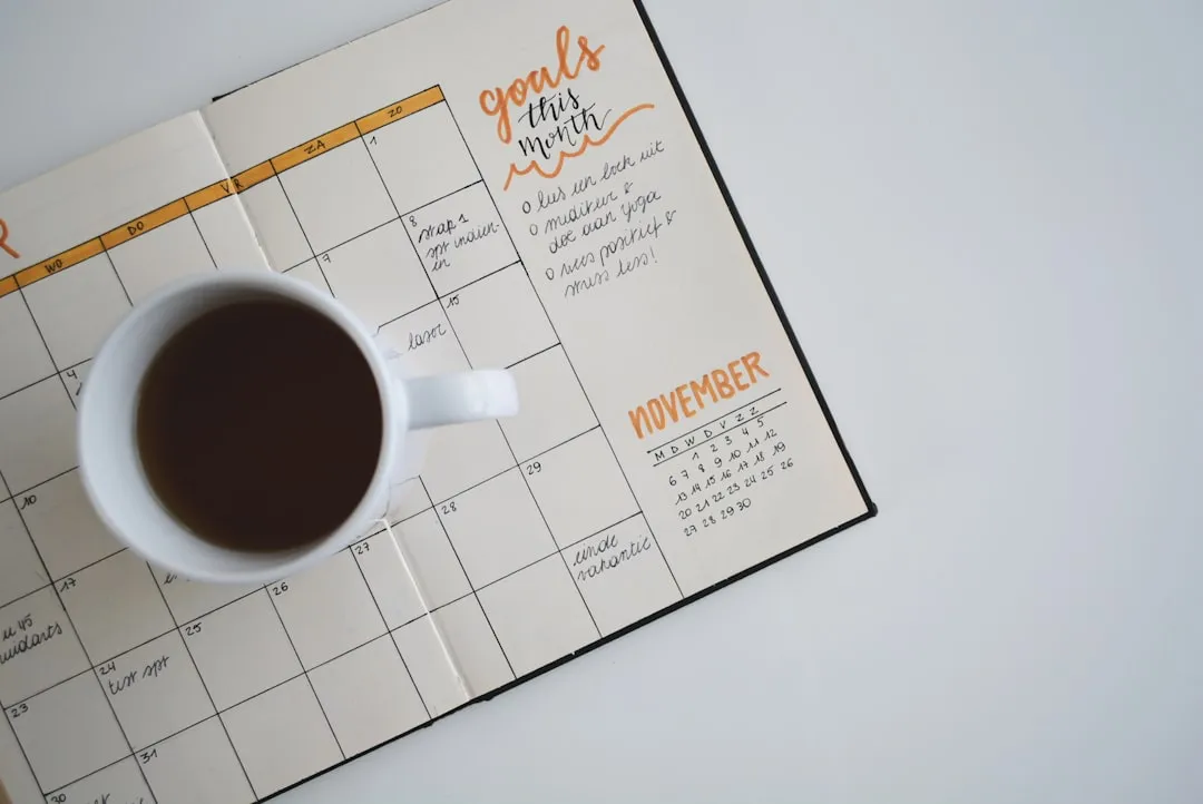 Caneca de cerâmica branca com café em cima de um planner Caneca de cerâmica branca com café em cima de um planner