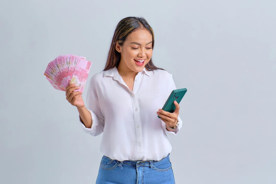 Uma mulher segurando um leque de dinheiro e um telefone celular
