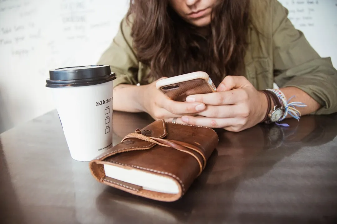 Mulher sentada à mesa enquanto usa smartphone